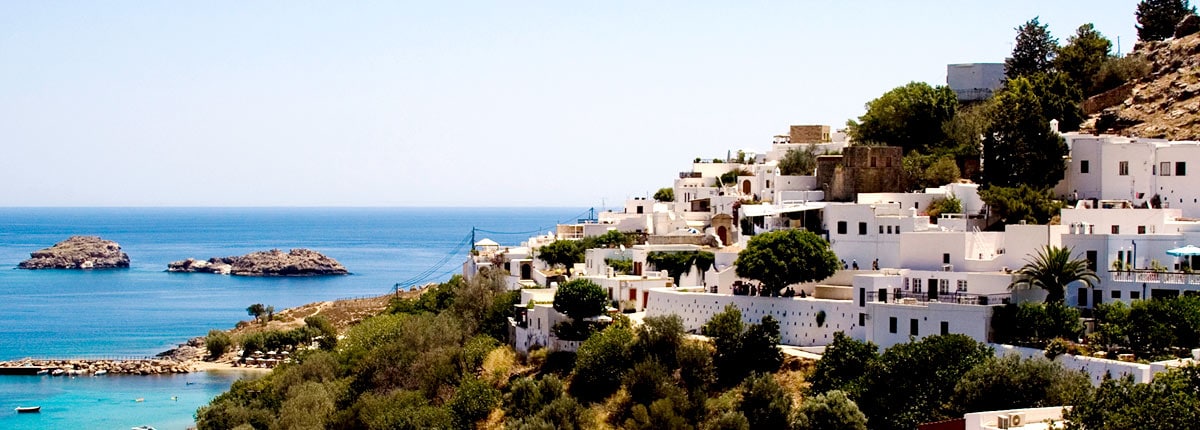 houses perched on a hill along the rhodes coastline