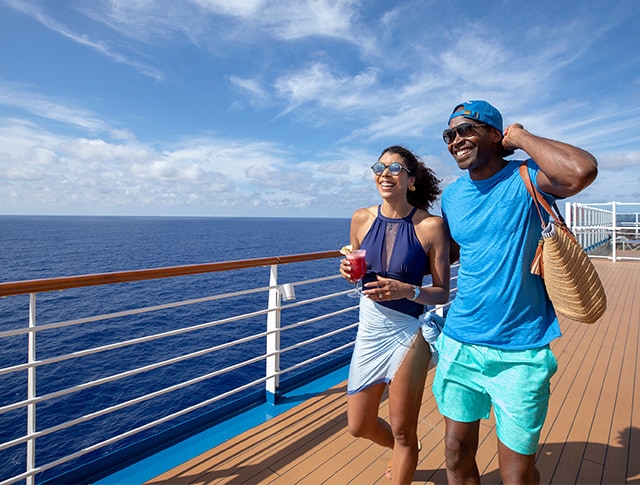 couple smiling and walking on the upper deck of a ship