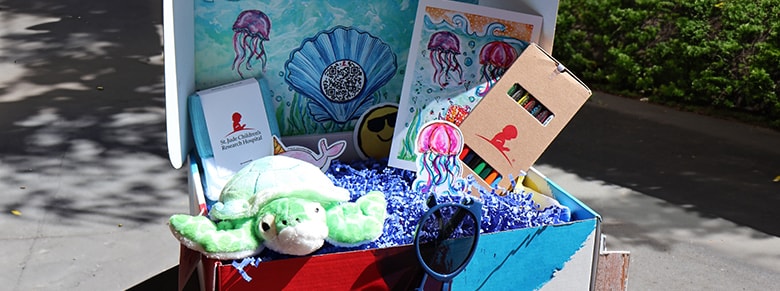 stuffed animal, sunglasses and coloring books with crayons inside a birthday box