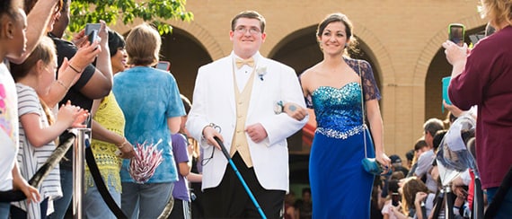 couple walks down a red carpet to the spring formal