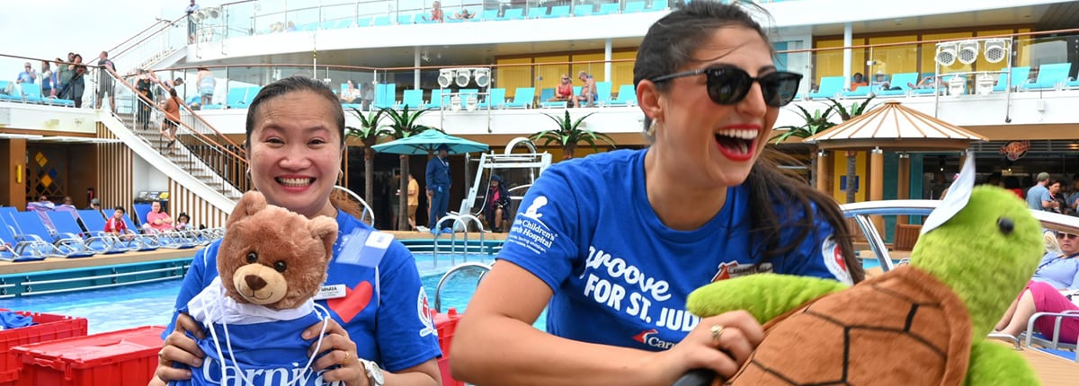 two women in blue shirts on a carnival ship celebrating for St Jude