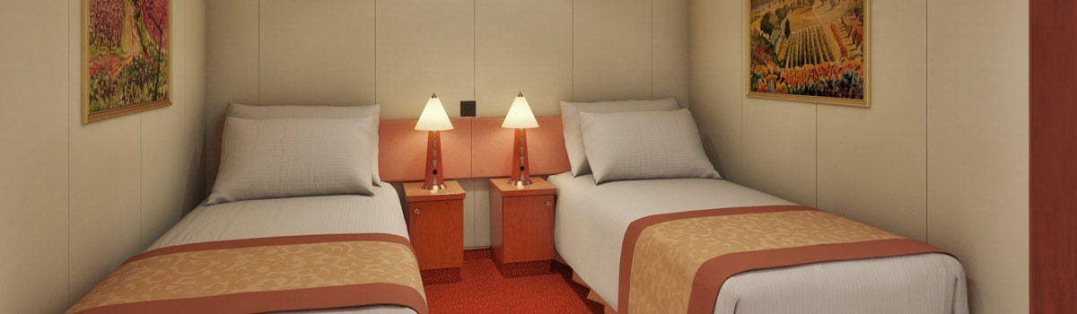 Interior stateroom aboard Carnival Glory with a bed, seating area, and wall art
