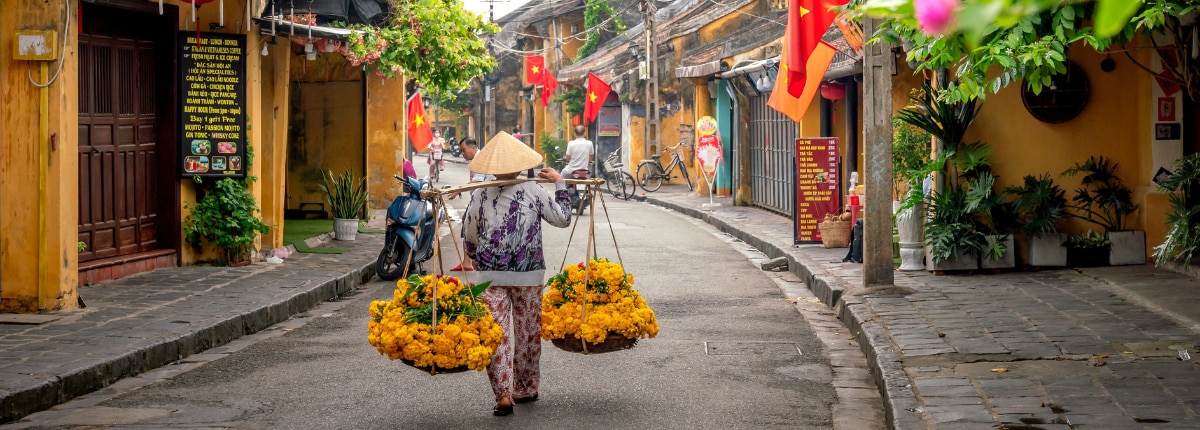 flower vendor walking through a traditional street in chan may vietnam