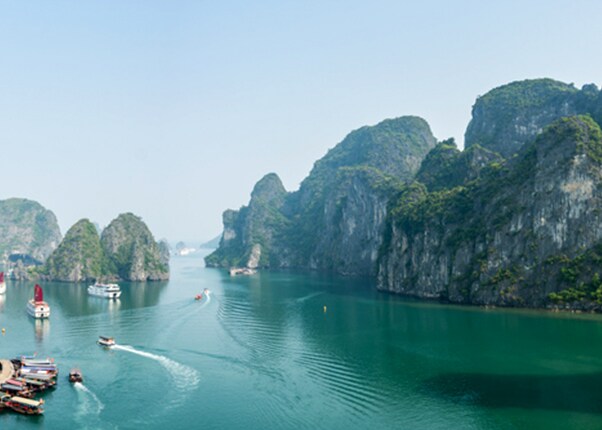 boats cruising through ha long bay Vietnam surrounded by limestone islands and emerald waters