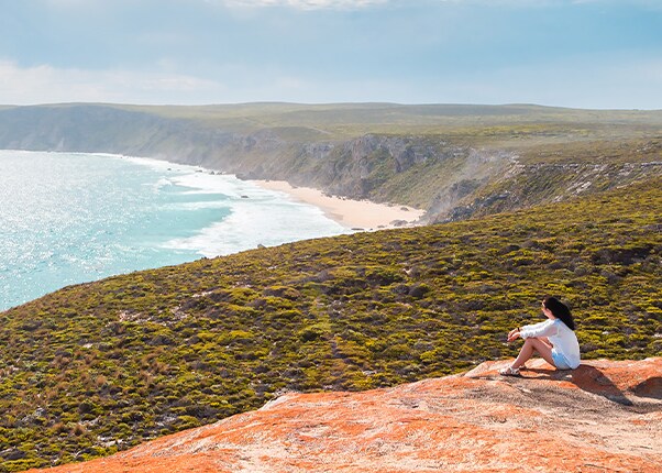 a woman sits on a large rock located in kangaroo island