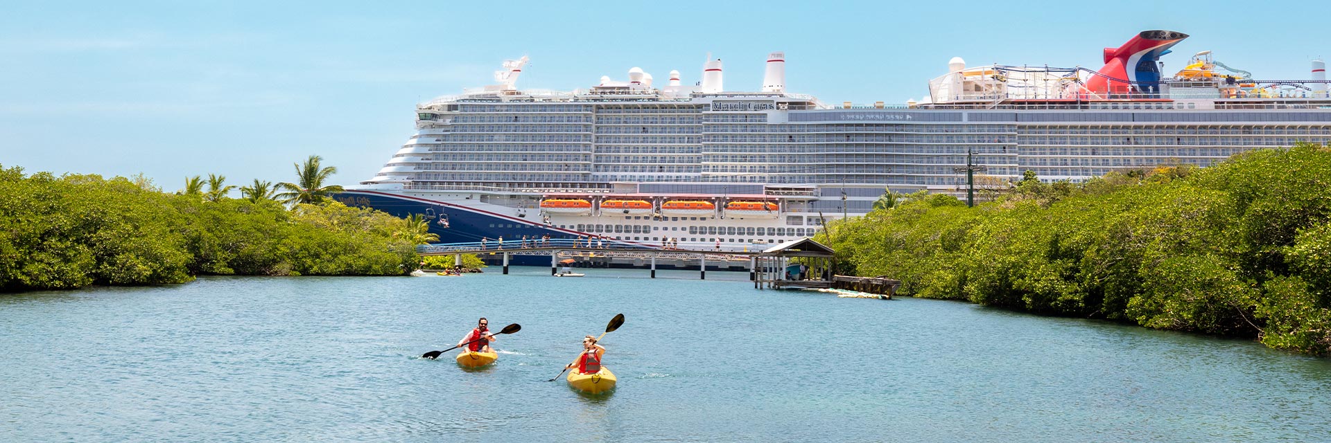 guests kayaking in front of a carnival ship at isla tropicale