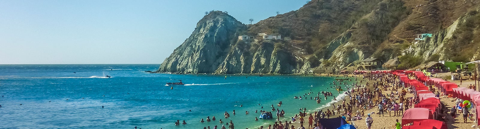 Colorful umbrellas and sun worshipers enjoying the beach in Santa Marta, Columbia