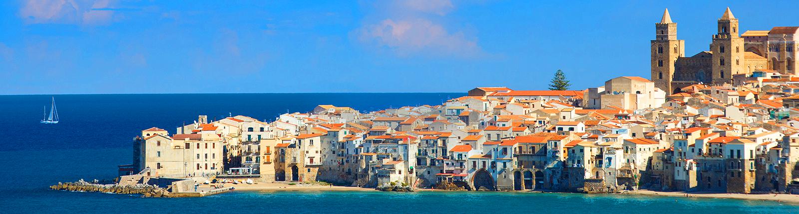Red rooftops set against the blue waters on the seaside of Cefalu, near Palermo, Italy