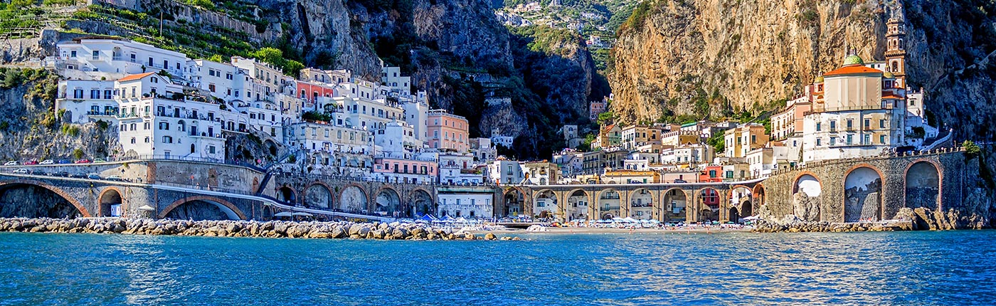 buildings by the water with a backdrop of mountains