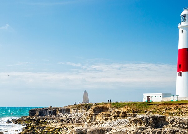 a red and white lighthouse is located on the edge of a cliff