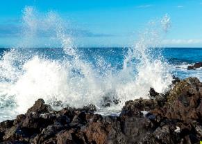 waves crashing into the rock lined coastline in kona