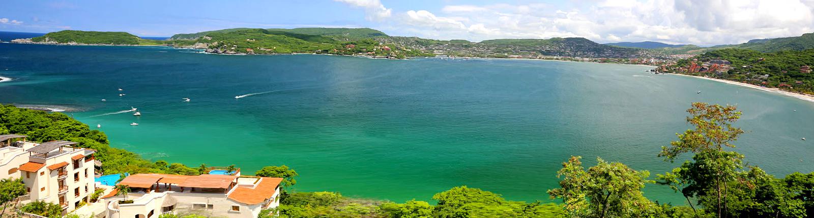 Aerial view of a body of water with homes near by in Zihuanatejo, Mexico