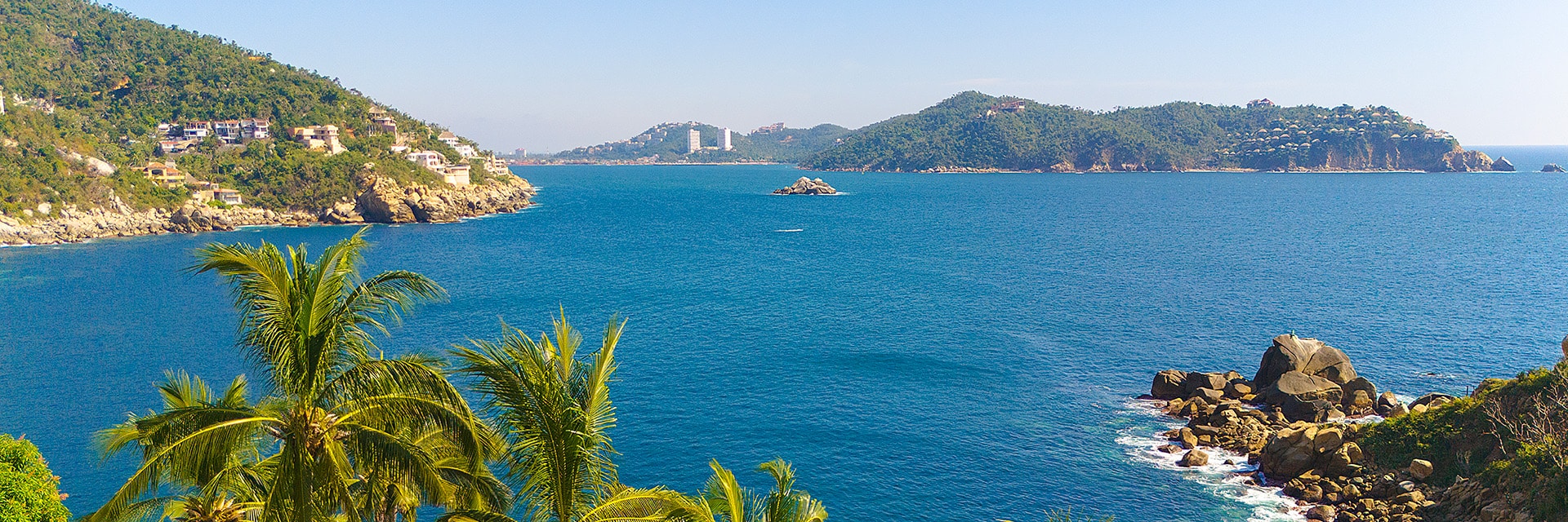 bay of rocky coast in acapulco with palm trees