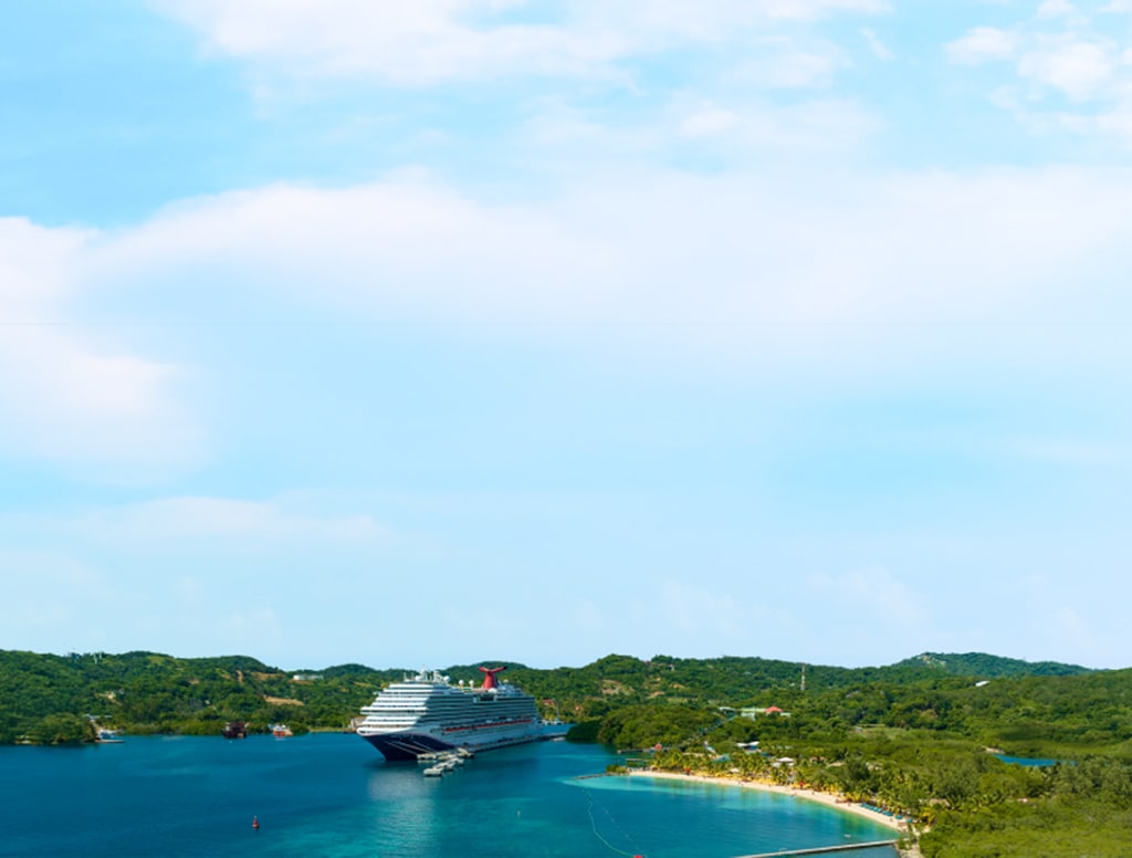 view of a carnival ship docked at isla tropicale roatan