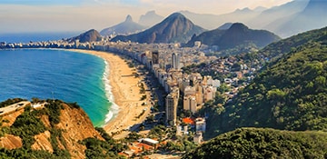the long stretch of copacabana beach with mountains in the background in brazil