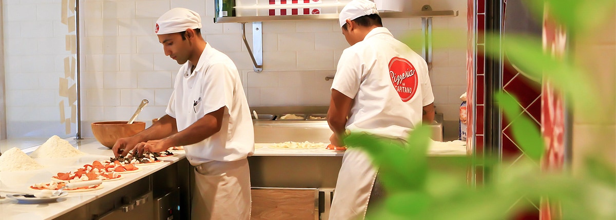 two pizza chefs making pizzas inside pizzeria del capitano