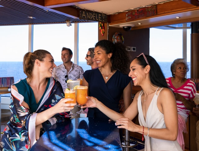 group of ladies cheersing with their tropical drinks onboard a carnival cruise