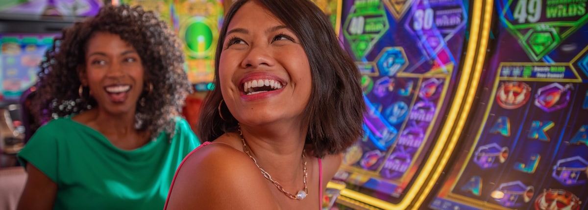 two women smile while they play at the slot machines
