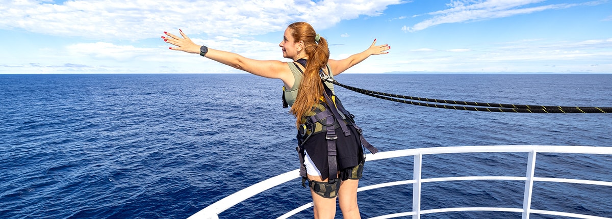 guest standing on a railing wearing a safety harness
