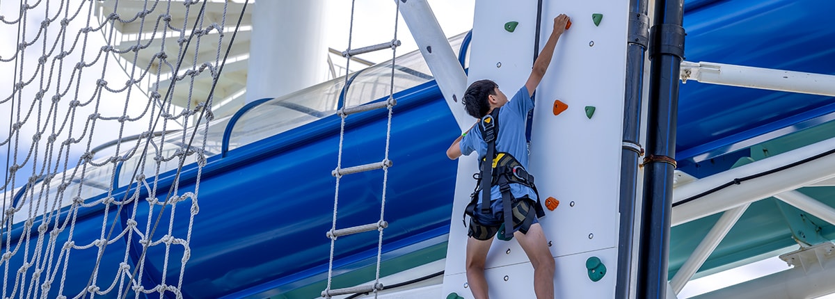guest climbing up a rock wall onboard a carnival cruise