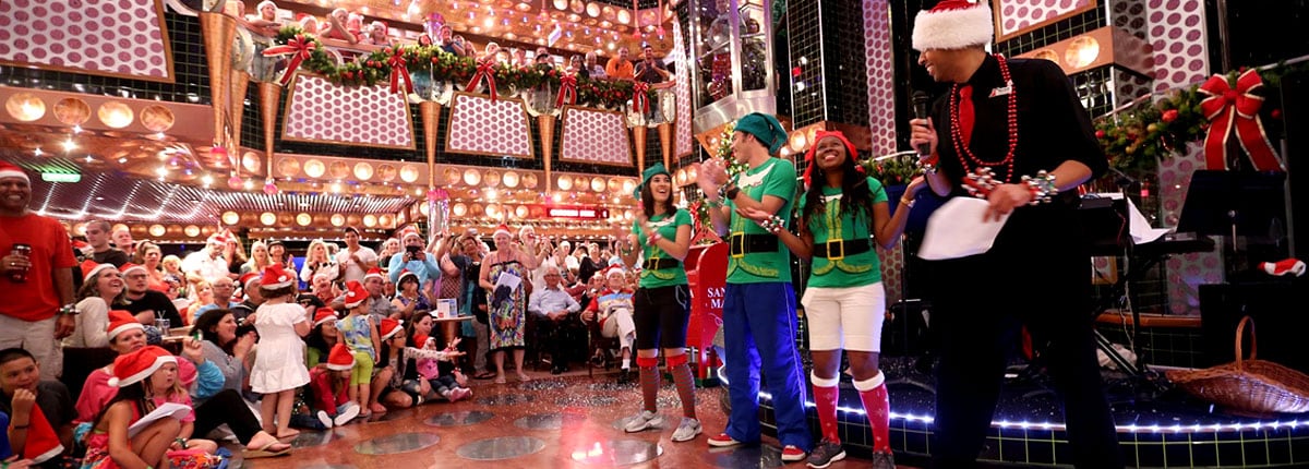 group of people gathered for Christmas festivities in the atrium of a Carnival cruise