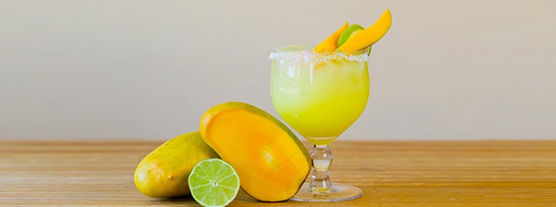 a delicous mango margarita garnished with a few mango and limes 