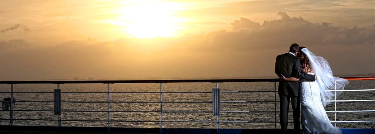 a couple looking over the water after their wedding on a carnival cruise