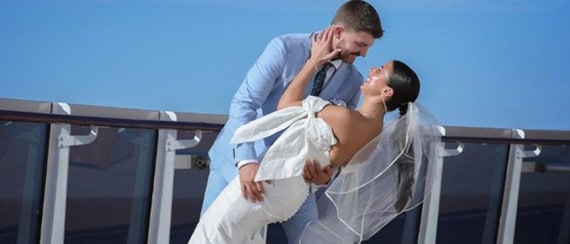 man and woman looking at her wedding ring on a carnival ship with red funnel in the background
