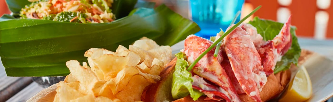 lobster roll with large chunks of lobster plus side of veggies wrapped in banana leaf and chips