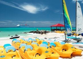 paddleboats and wind surfing kayaks lined on a beach in princess cays