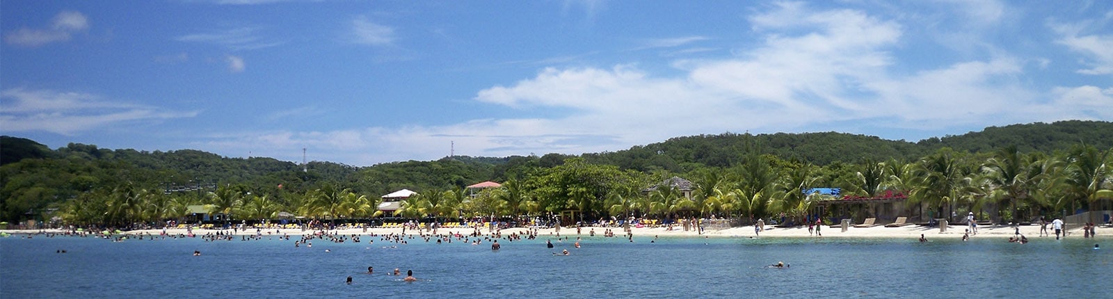 People swimming in the warm blue ocean off the beach in Mahogany Bay, Isla Roatan