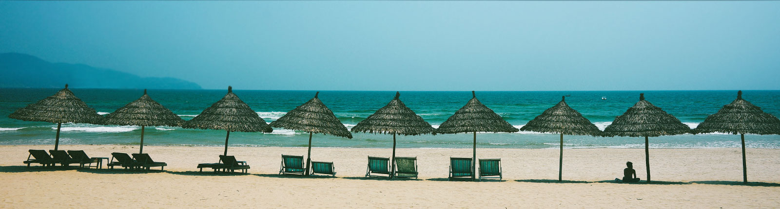Thatched umbrellas lined up along the beach in Mahogany Bay, Isla Roatan