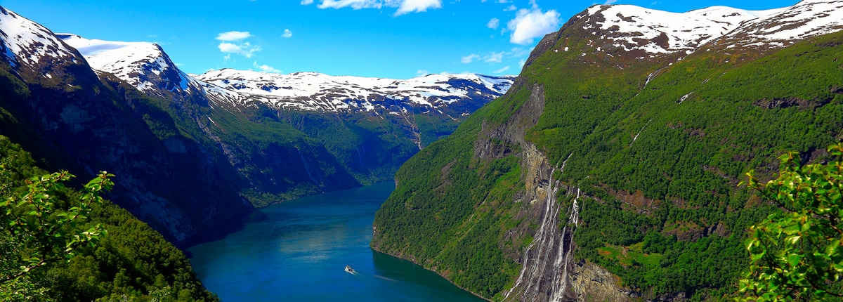 a small boat cruises in a fjord surrounded by mountains