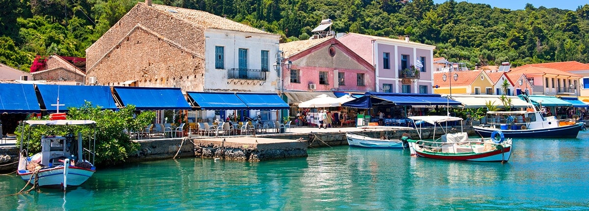 colorful boats and shops line the pier in katakolon, greece