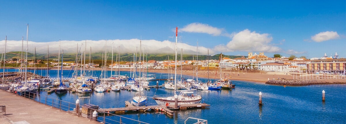 view of boats at the dock along crystal blue waters in praia da vitoria, azores