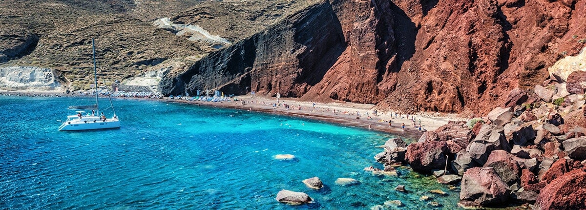 moutainous red beach with clear, teal water in santorini, greece