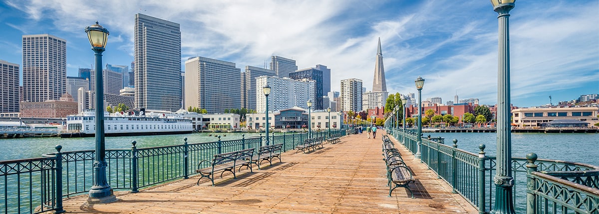 a bridge extends across water with the city of san francisco at the end