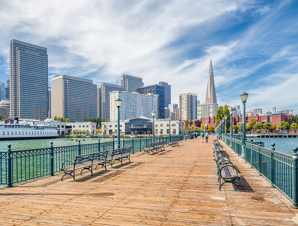 a bridge extends across water with the city of san francisco at the end