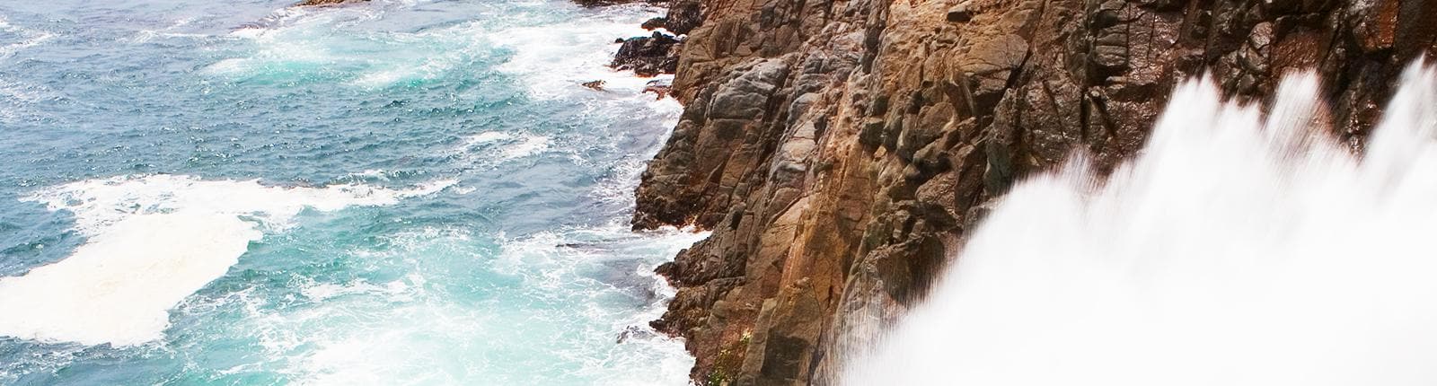 Waves crashing onto a beautiful natural rock formation along the coast of Ensenada, Mexico