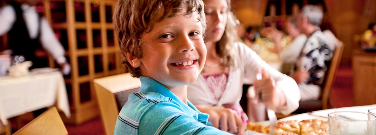 a boy smiles while eating his delicious kids menu meal 