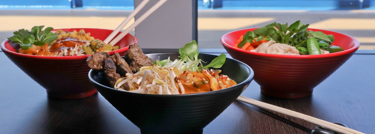 three bowls of asian cuisine from lucky bowl on a table by a window overlooking the sea