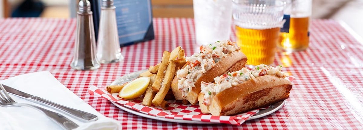 a seafood sandwich with fries and a drink is on display at seafood shack