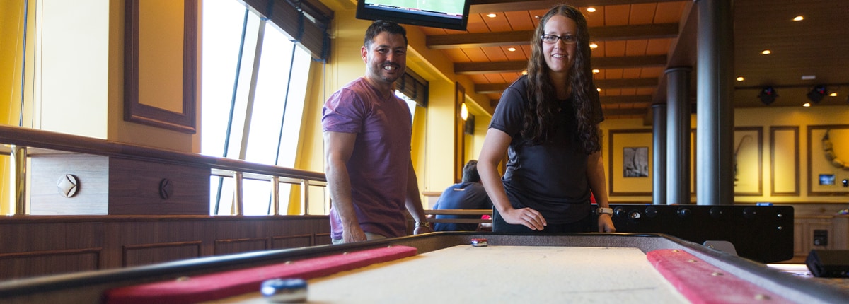 guests play a game of table shuffleboard at redfrog pub