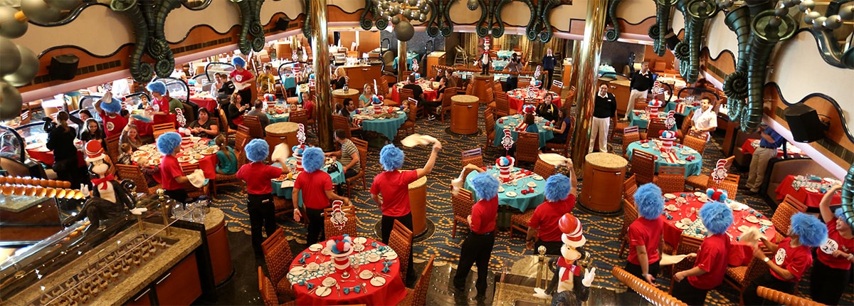 dining room setting with carnival staff wearing wigs and twirling napkins