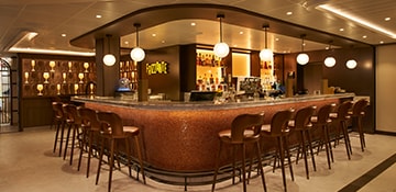 a background wall of different wine glasses and brown chairs at the counter of the frizzante bar