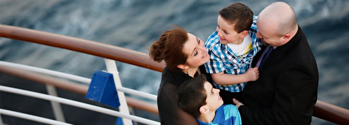 a family of four smiles and embraces each other on deck
