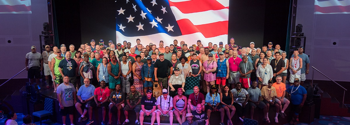 group of carnival military guests posing for a photo on stage with the american flag in the background