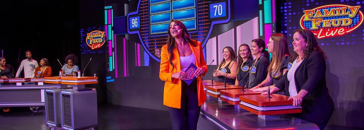 family feud live game show host standing in front of contestants on stage