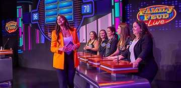 family feud live game show host standing in front of contestants on stage