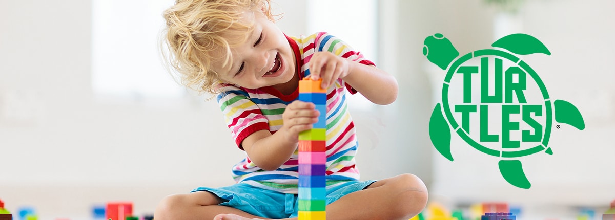 a young child plays with a block of toys; turtles program registered logo